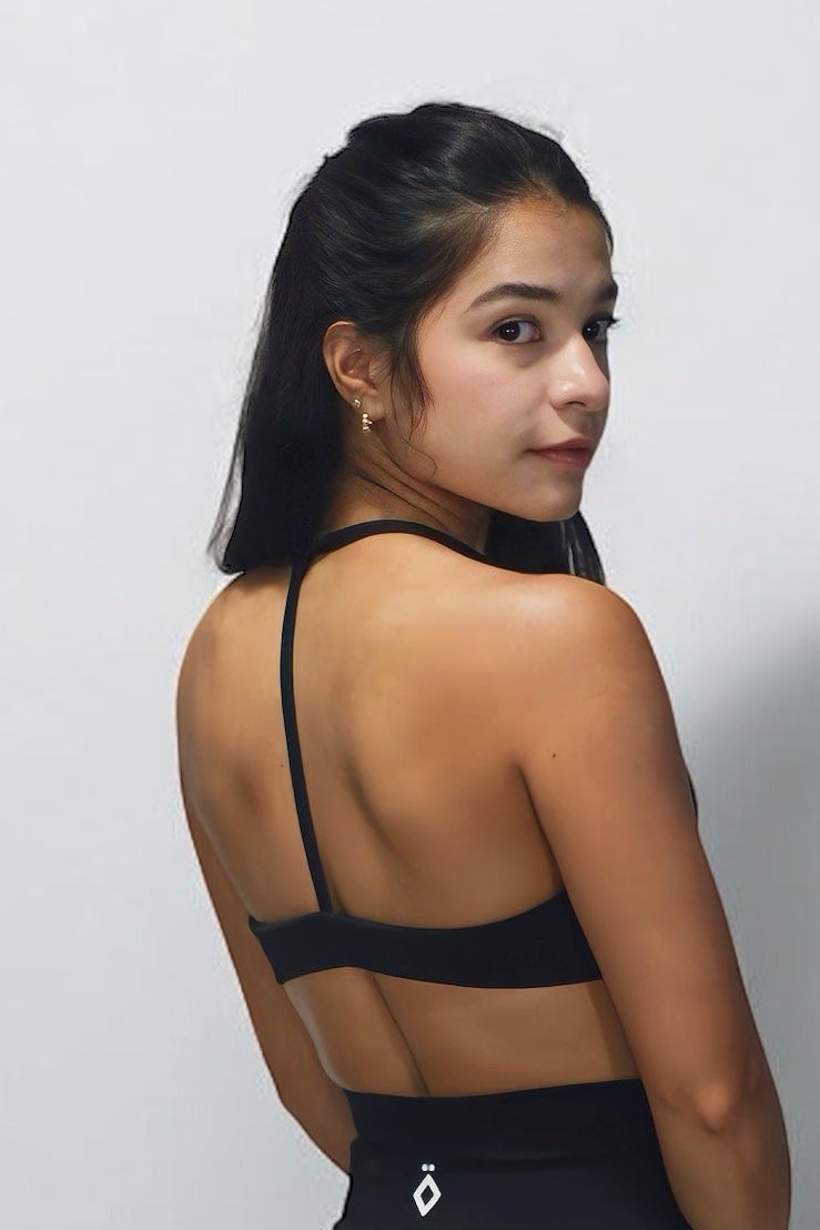 Person wearing a black outfit with open back on a plain background