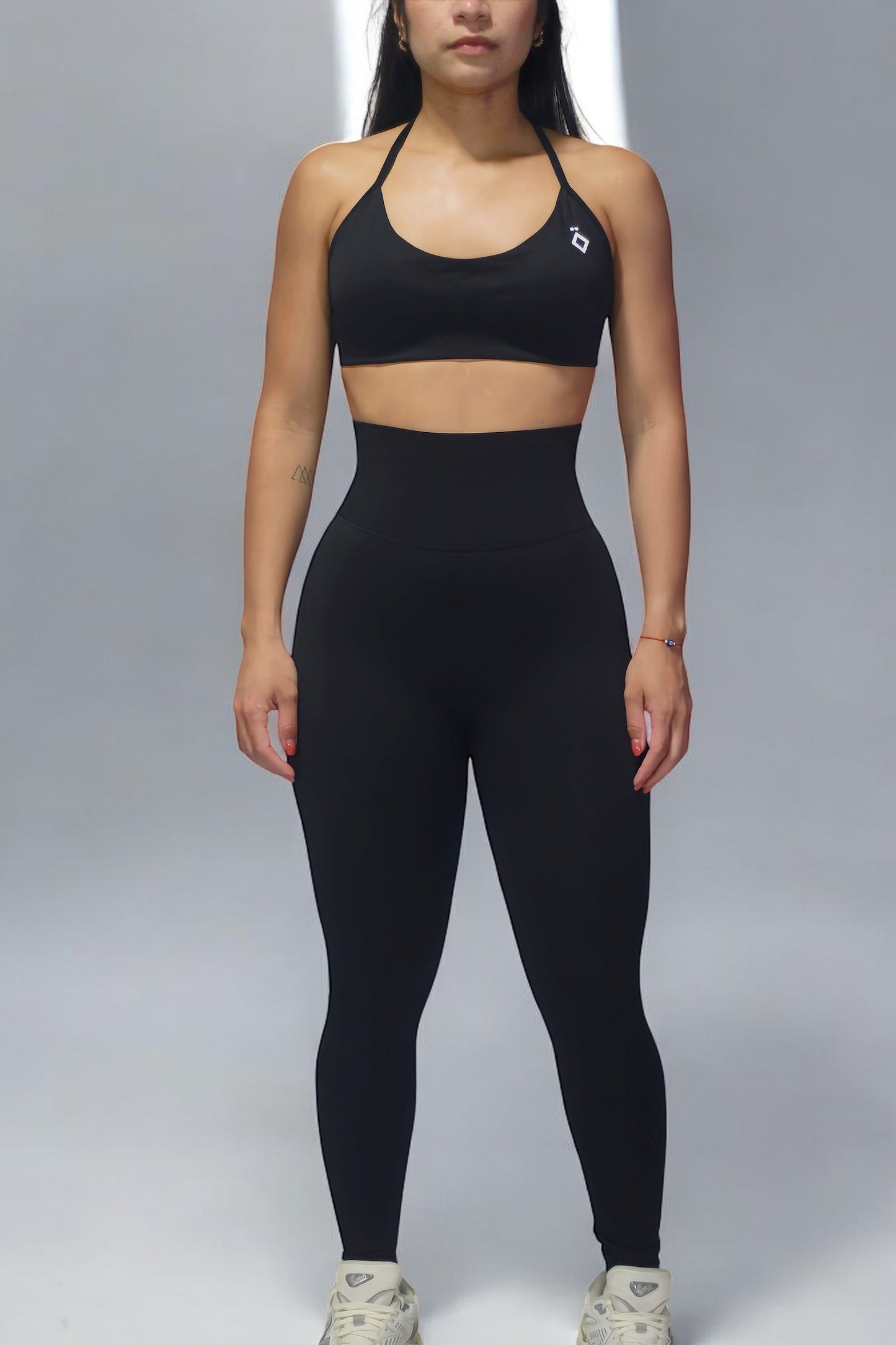 Woman wearing a black sports bra with a logo on a gray background