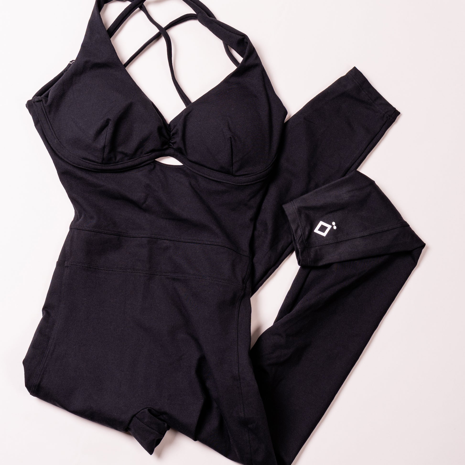 Black jumpsuit with strappy top and matching pants on a white background