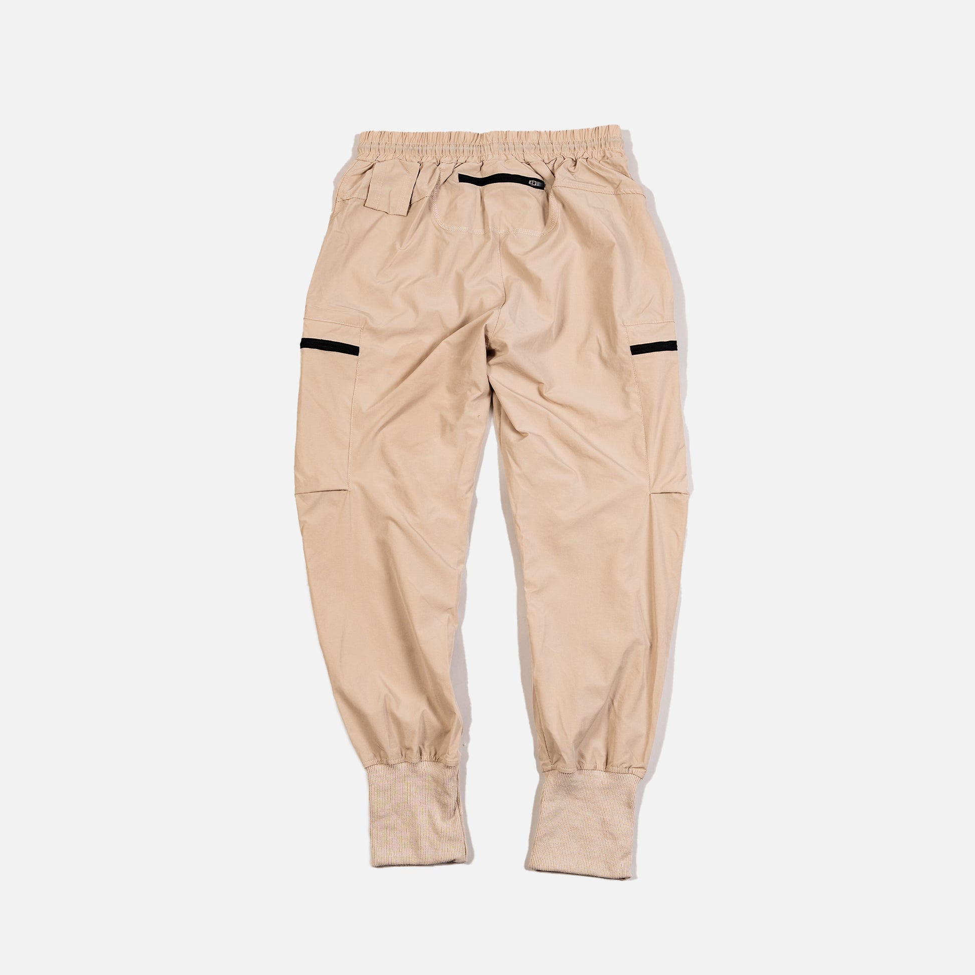 Beige jogger pants with black accents on a light gray background