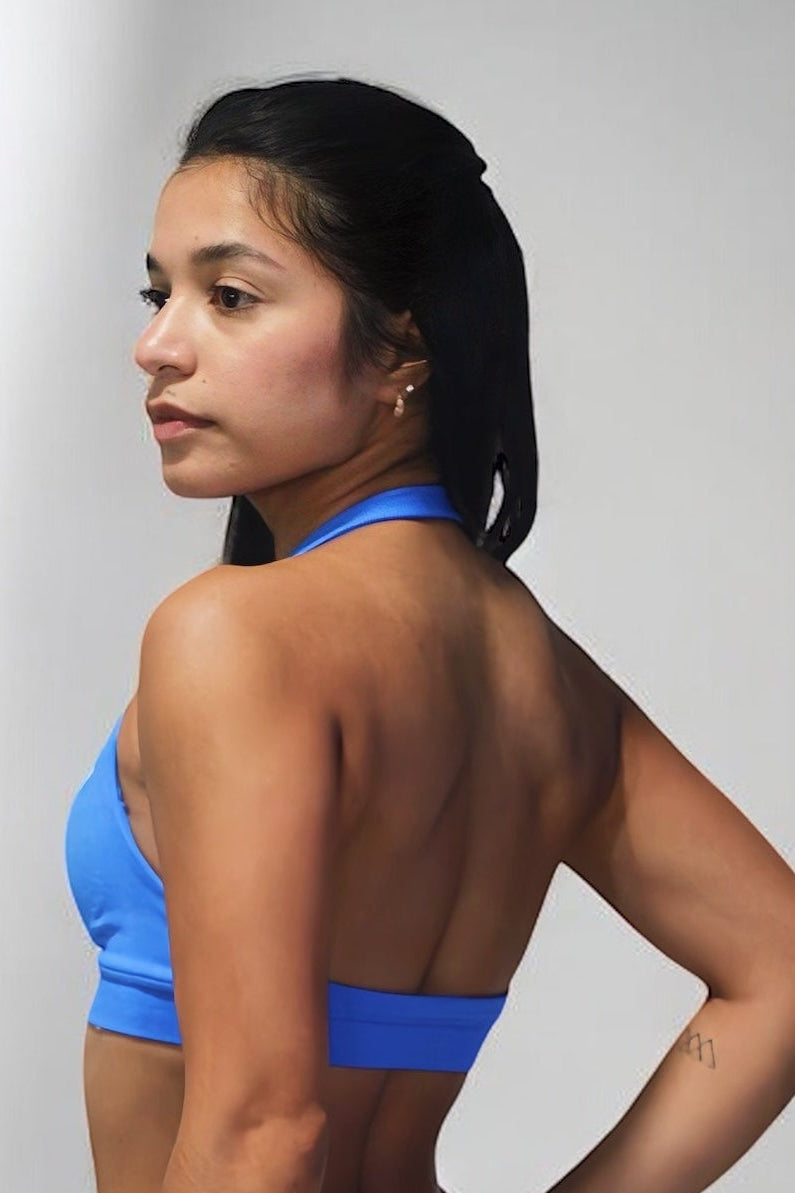 Woman wearing a blue sports bra and leggings against a plain background