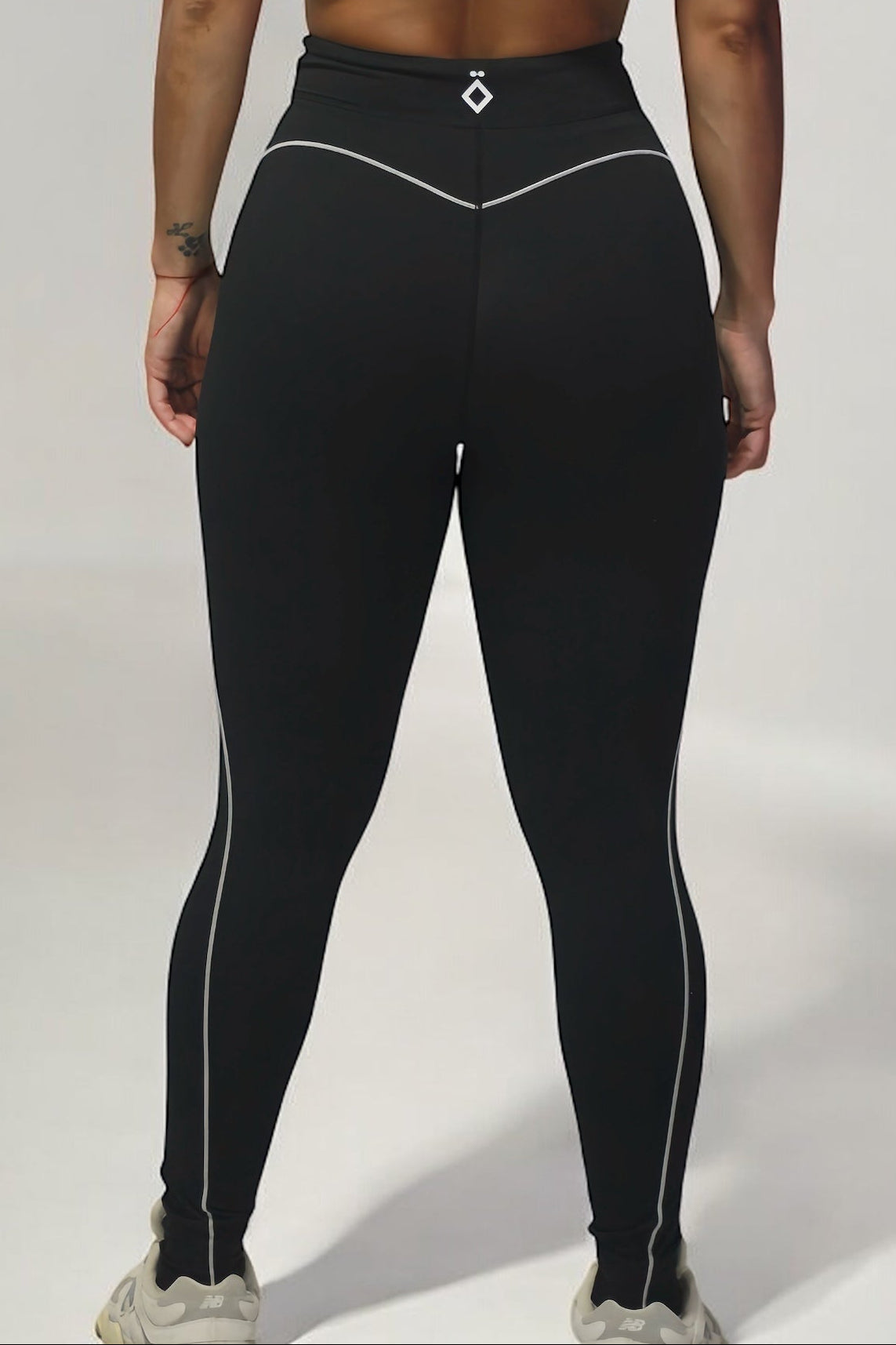 Person wearing a black athletic outfit with white accents on a plain background
