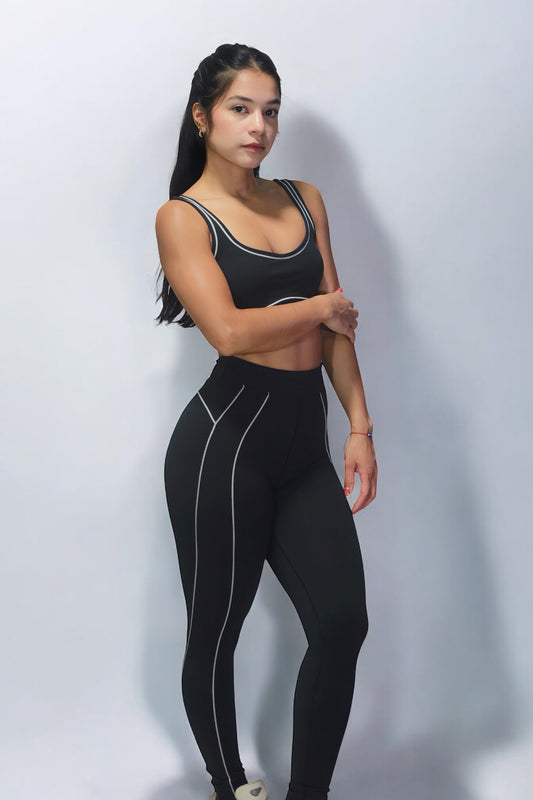 Woman wearing a black athletic outfit with white stripes on a light gray background